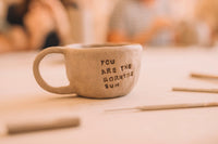 Hand built mug with handle reading "you are the morning sun," Clay & Wine class, Nambour
