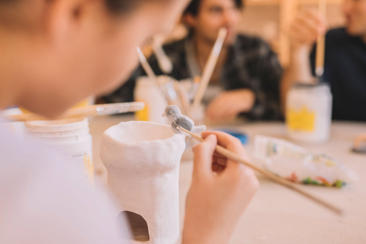 Student glazing their own pottery piece in class, Nambour