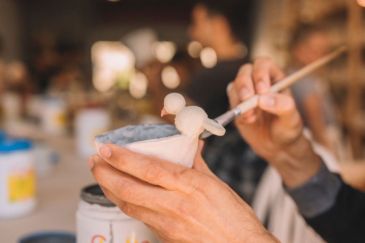 Close-up of student's hands applying glaze to pottery, Nambour