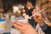 Close-up of student's hands applying glaze to pottery, Nambour
