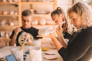 Students painting glaze onto pottery in glazing class, Nambour