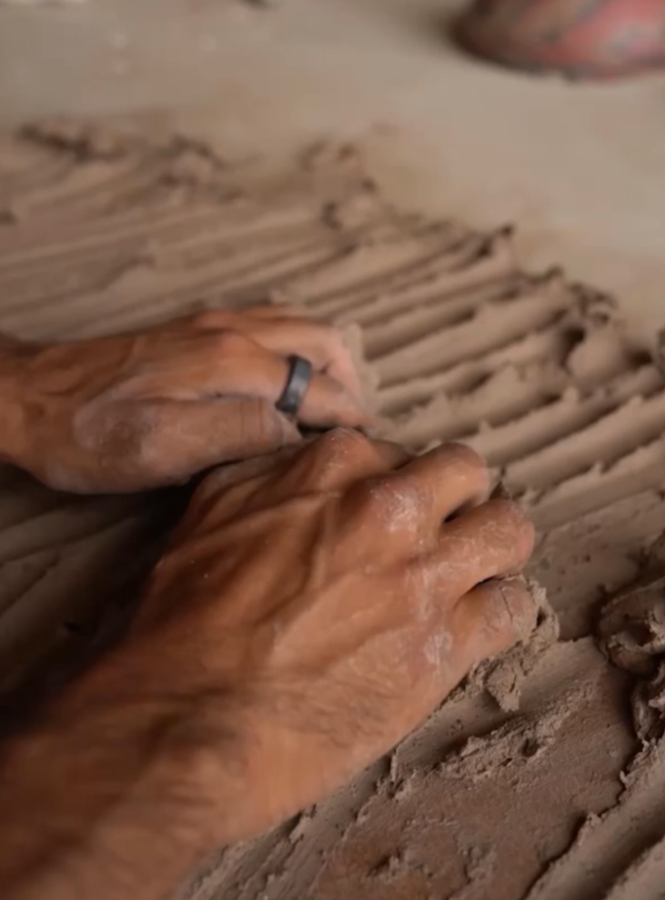 Scraping clay off the work table with fingertips, Nambour pottery studio