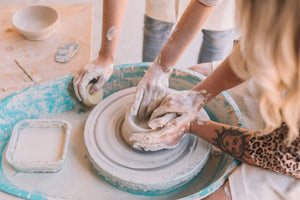 Instructor and student hands shaping clay together in wheel throwing class, Nambour